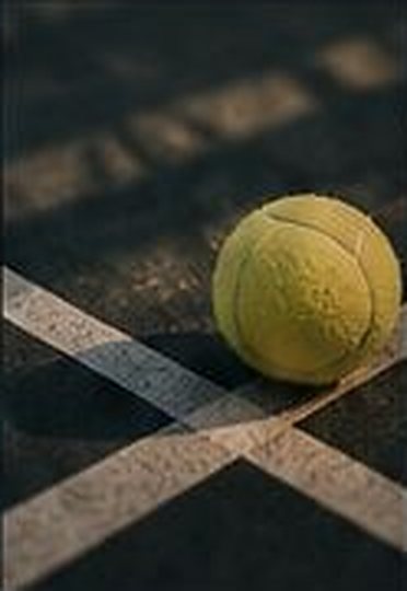 Balle de tennis posée sur la ligne de fond de court